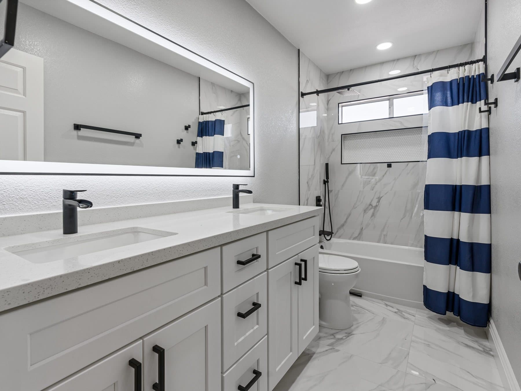 Summerlin bathroom remodel: vanity with illuminated mirror beside the tub
