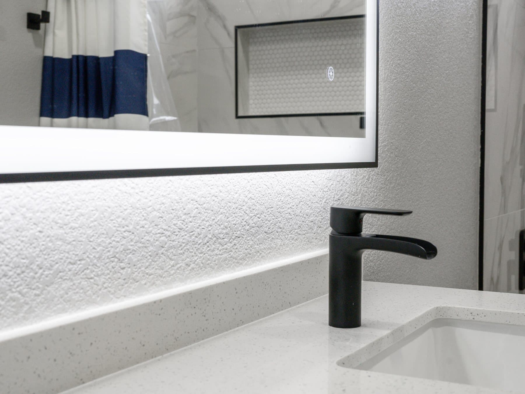 Summerlin bathroom remodel: matte-black faucet under an illuminated mirror
